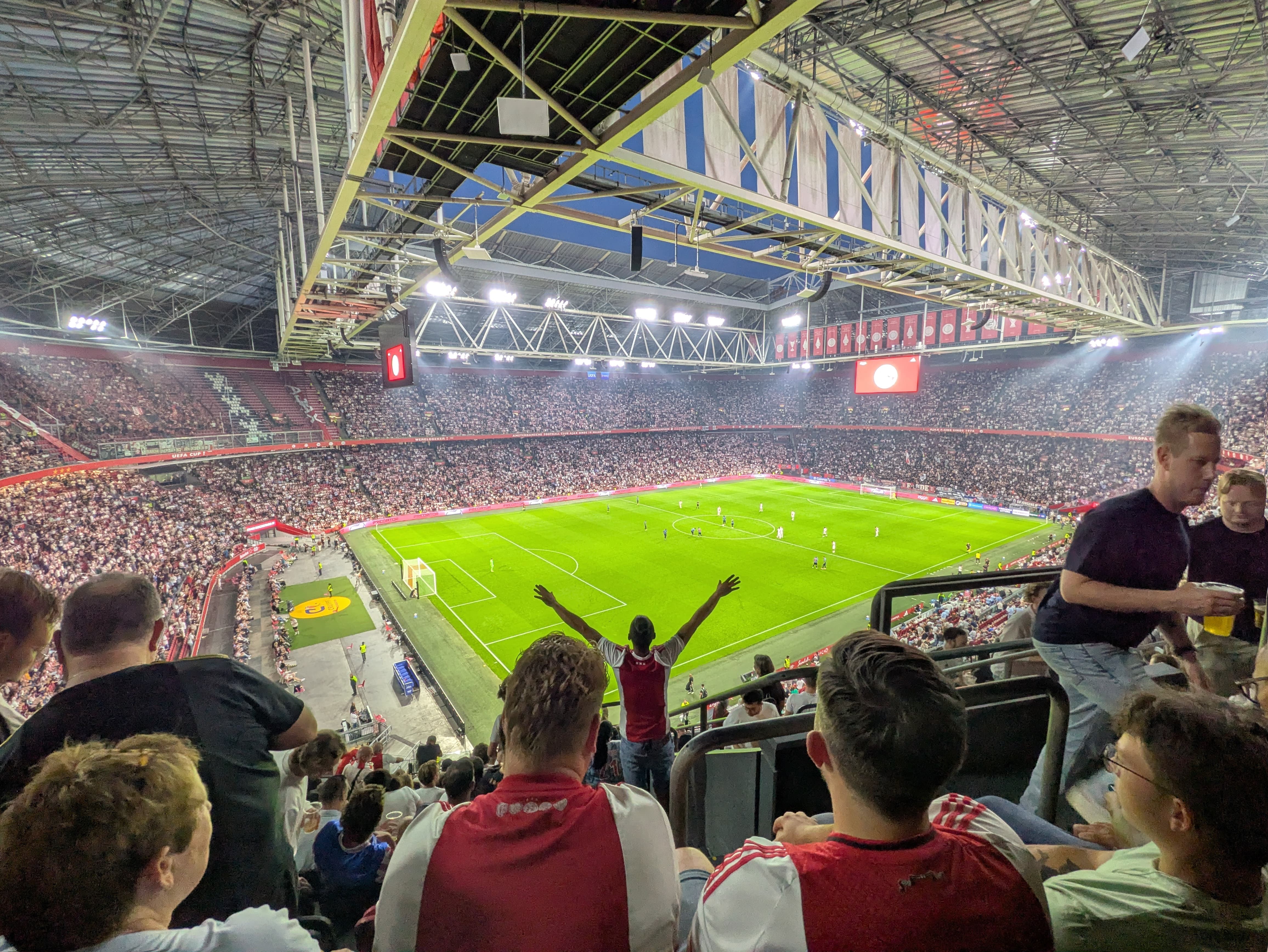 Wedstrijdafbeelding Ajax-Sion op de bovenste ring in het stadion, met een juigende fan
